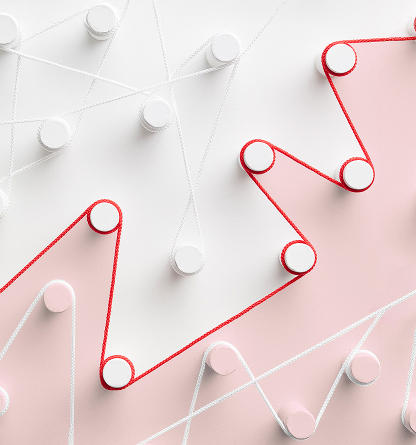 Abstract image of red and white cords woven in zigzag patterns around circular pegs on a soft pink and light gray background. The cords create intersecting geometric lines across the image, with the red cord standing out prominently against the muted pastel colors. The composition has a clean, minimalist design and conveys the idea of interconnected paths or processes.