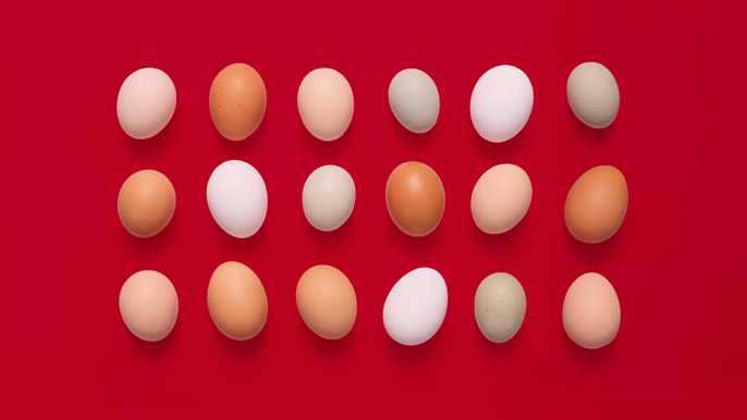 different colored and shaped eggs on red background